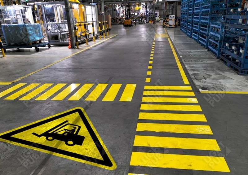 Entrepôt industriel avec marquage au sol de sécurité et signalétique de rayonnage conforme aux normes.